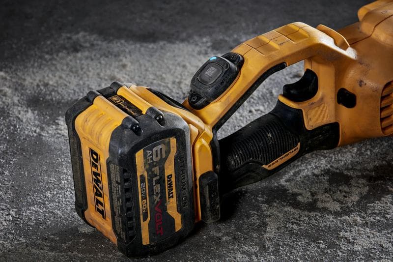 Gros plan sur un outil électrique sans fil DEWALT avec une batterie FlexVolt de 6 Ah attachée, montrant la poignée et la batterie sur une surface en béton.