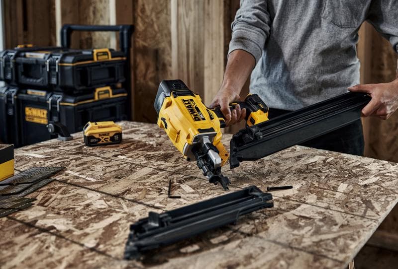 Cloueur DEWALT DZN930-XJ, DZN930 utilisé sur du contreplaqué, boîte à outils et batterie visibles.