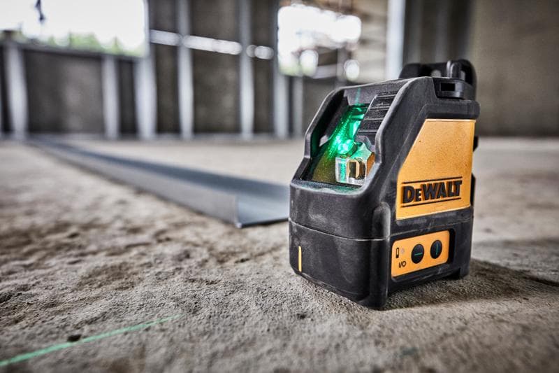 Niveau laser à faisceau vert DEWALT DW088CG sur sol en béton d’un chantier.