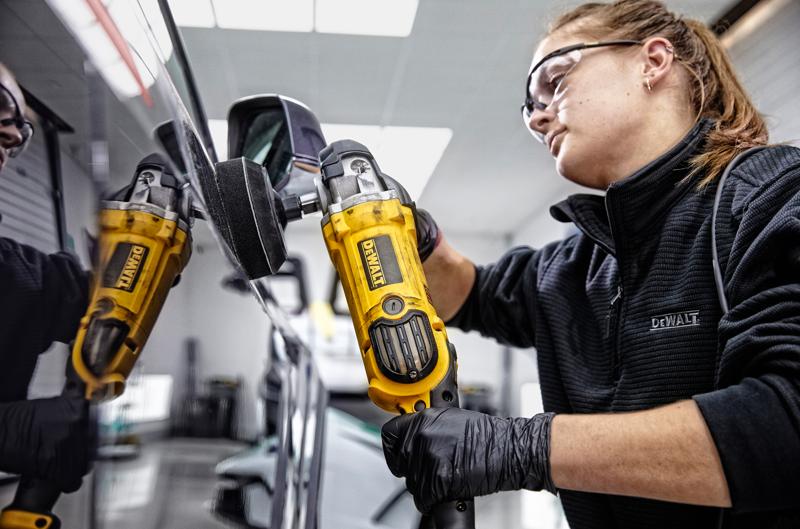 Personne utilise une polisseuse jaune DEWALT DWP849X sur un rétroviseur de voiture. Visage flouté.