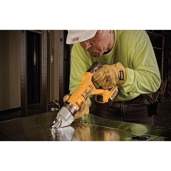 A worker wearing a hard hat and gloves uses a yellow DEWALT cordless metal shear tool to cut sheet metal.